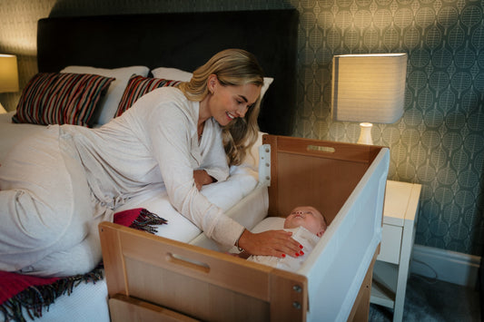 mum looking at her baby who is laying in the Huddle bedside crib
